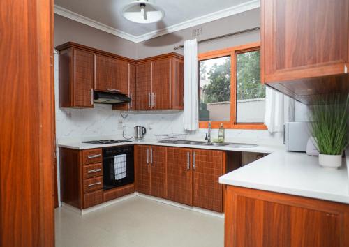 Una cocina con armarios de madera y una ventana. en Niza Homes, Pool, No Blackouts & Walk to Munali Mall, en Lusaka