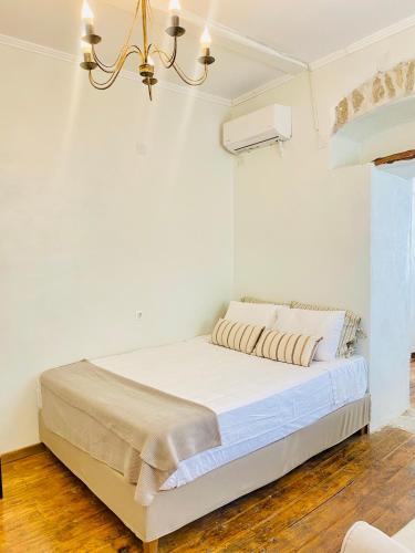a white bedroom with a bed with a chandelier at Dinateli Houses - Live like a local in Corfu in Kastellánoi