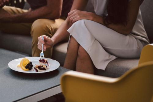a woman sitting on a couch with a plate of food at Après Post Hotel in Stuben am Arlberg