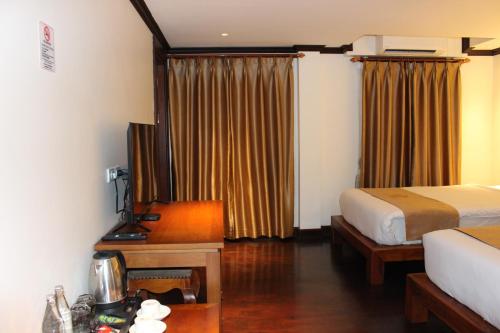 a hotel room with a bedroom with a bed and a table at Lux Hotel in Luang Prabang