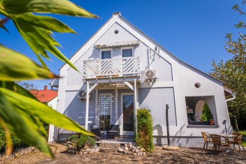 a white house with a porch and chairs at BELYSIUM B&B Wine&Relax Vendégház in Gyenesdiás