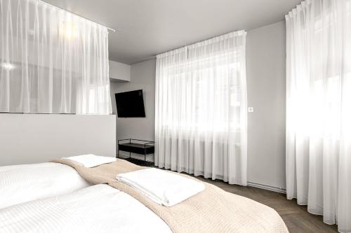 a white bedroom with white curtains and a bed at The Swan House by Heimaleiga in Reykjavík