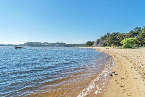 a sandy beach next to a body of water at Åros Seaside Apartment with Pool, Jacuzzi & Sauna in Kristiansand