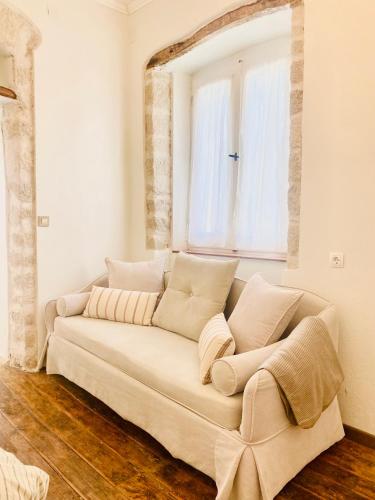a white couch in a room with a window at Dinateli Houses - Live like a local in Corfu in Kastellánoi