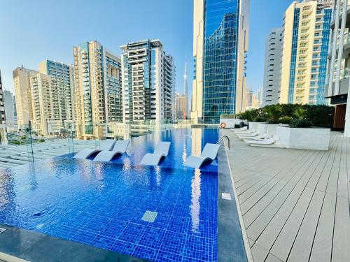 a swimming pool with white chairs in a city at Luxury Studio Bayz By Danube Business Bay Marasi Drive Dubai in Dubai