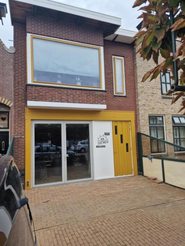 a building with a yellow and white door at Die Meid in Sint Maartensdijk