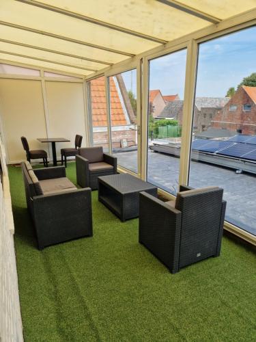a patio with chairs and a table and windows at Die Meid in Sint Maartensdijk