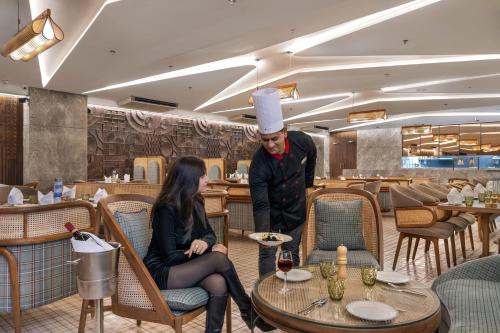 a chef standing next to a woman in a restaurant at Ramada Encore by Wyndham Ambala GT Road in Ambāla