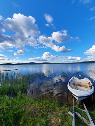a boat sitting on the shore of a lake at Camp Caroli Wooden Cabins in Jukkasjärvi
