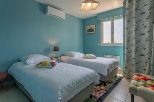 deux lits dans une chambre aux murs bleus dans l'établissement Le PLEIN SUD, à Agay