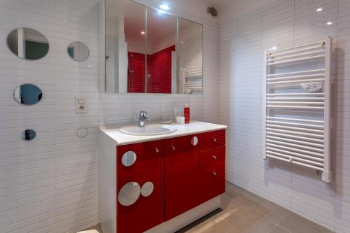 La salle de bains est pourvue d'un lavabo rouge et d'un miroir. dans l'établissement Le PLEIN SUD, à Agay
