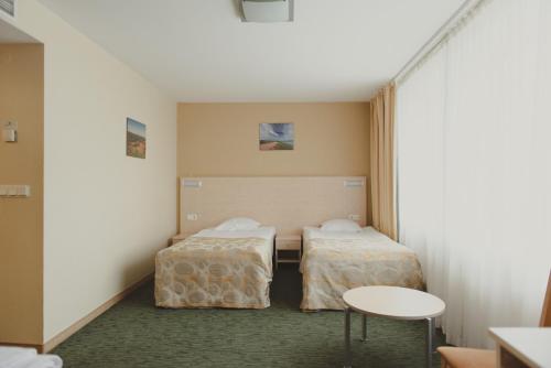 a room with two beds and a table at Park Hotel Latgola in Daugavpils
