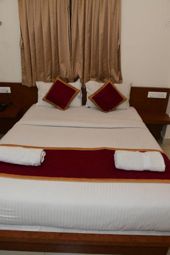 a bedroom with a large bed with two pillows at Sai Vihaar Inn & Suites in Mysore