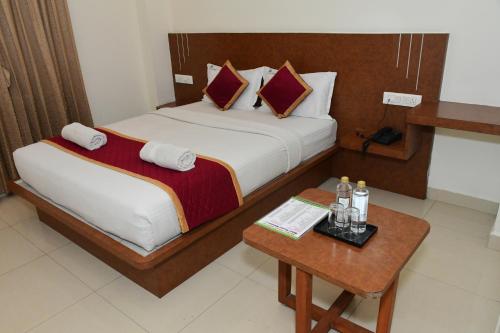 a hotel room with a bed and a table at Sai Vihaar Inn & Suites in Mysore