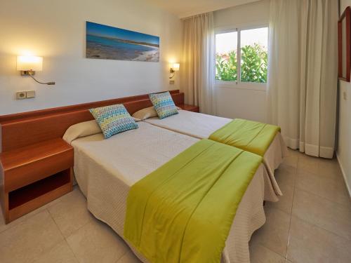 a hotel room with a bed and two windows at Aparthotel Ciudad Laurel in Cala Millor