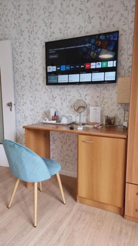 een bureau met een blauwe stoel en een televisie aan de muur bij Maison Susy in Sant'Agnello