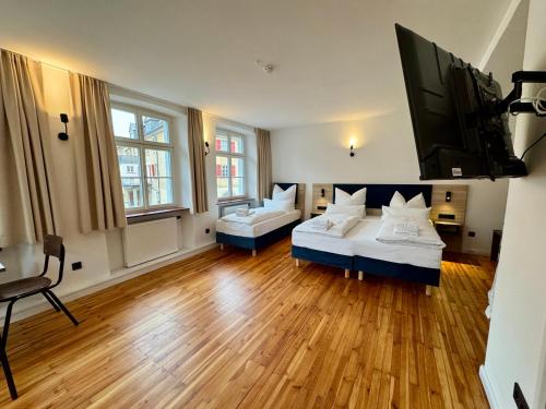 a large room with two beds and a flat screen tv at Hopfenhotel am Adenauerufer in Bamberg