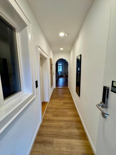 a hallway with white walls and wood floors at Hopfenhotel am Adenauerufer in Bamberg