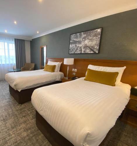 a hotel room with two beds and a table with a chair at Crowne Plaza East Midlands Airport by IHG in Derby