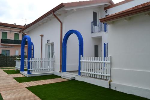 a white house with blue doors and green grass at B&B Residenza Marina in Marina di Carrara
