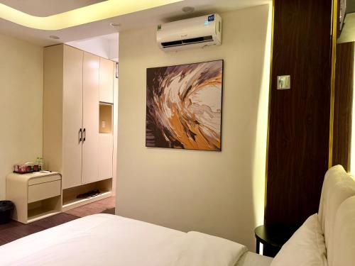 a bedroom with a bed and a painting on the wall at Star Night Hotel and Apartment in Hanoi