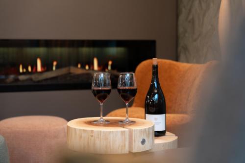 two glasses of wine on a table with a bottle of wine at Designhotel am Stadtgarten in Freiburg im Breisgau