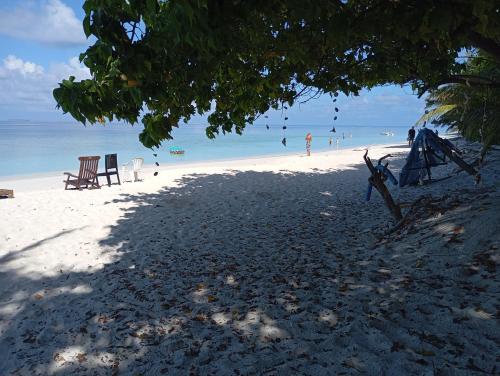 a beach with two chairs and people in the water at Seaview by Ukulhas in Filitheyo