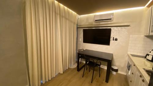 a kitchen with a table and a television in a room at Apart-hotel Theotókos Flats in Piumhi