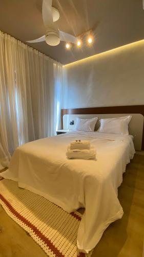 a bedroom with a white bed with a ceiling at Apart-hotel Theotókos Flats in Piumhi