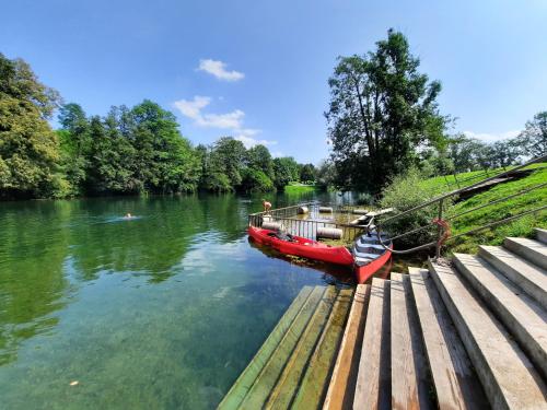a red boat on a river next to a dock at Počitniška hiša Parkfield Dragovan in Metlika