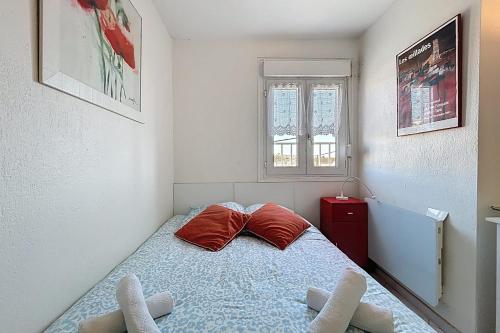 une chambre avec un lit avec des oreillers rouges et une fenêtre dans l'établissement Le Rouget - Proche du port et de la mer - Parking, à Fleury