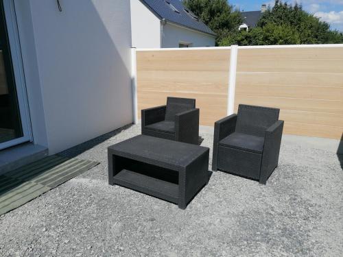 two black chairs and a stool next to a building at Studio cosy in Granville