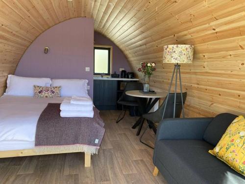 a bedroom with a bed and a couch and a table at Dingle Wild - Luxury Pod in Dingle