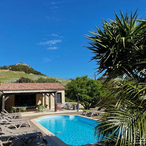 une piscine avec des chaises longues et une maison dans l'établissement Casa Eva Maria, à Patrimonio