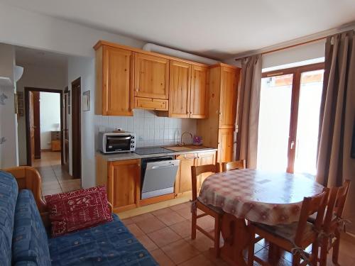 une cuisine avec des placards en bois et une table avec une nappe dans l'établissement Appartement rénové 2 pièces + coin montagne - 6 pers - Centre village près des pistes - 2* - FR-1-445-119, à Montgenèvre