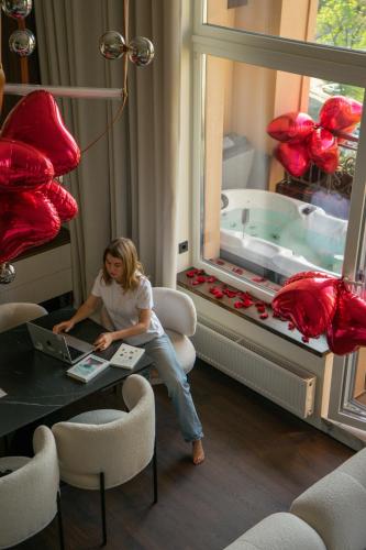 a woman sitting at a table in front of a tub at SkySpa Apartments - апартаменти з джакузі на терасі з видом на Печерськ in Kyiv