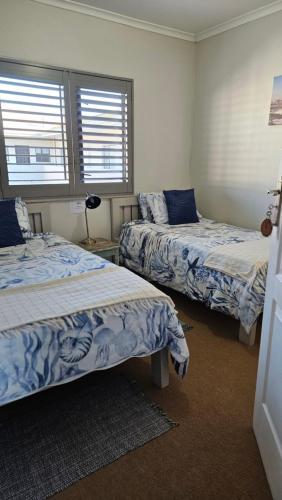 a bedroom with two beds and two windows at MADRIKO 36 Cozy self catering 2 bedroom apartment in Langebaan