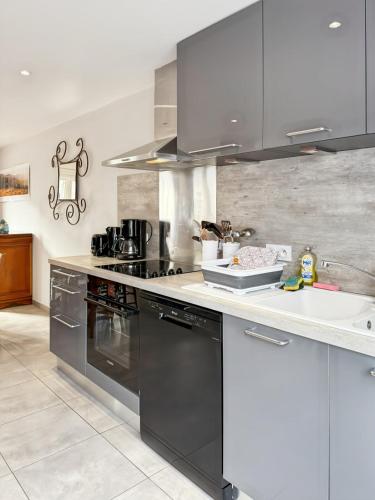 une cuisine avec des appareils noirs et un comptoir blanc dans l'établissement Vallée de la Jordanne, Maison cosy 6pers, terrasse, à Saint-Julien-de-Jordanne