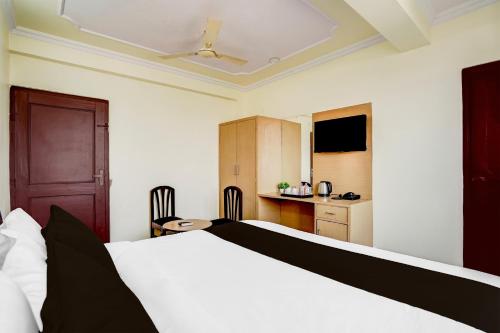 a bedroom with a white bed and a kitchen at Hotel O Heera Palace in Jaipur