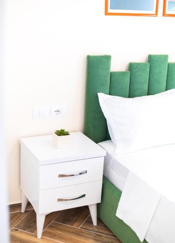 a white bed with a green headboard and a white nightstand at CAPTAIN'S RESIDENCE in Ksamil