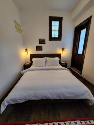 a large white bed in a bedroom with two windows at Sokak Boutique Hotel in Berat