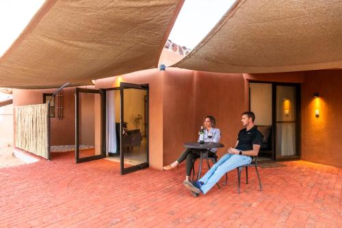a man and woman sitting at a table in a building at Barkhan Dune Retreat in Solitaire