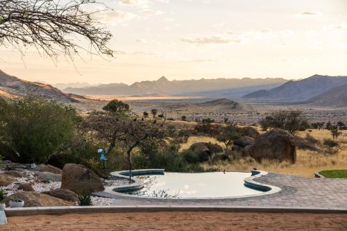 a pool in the desert with mountains in the background at Barkhan Dune Retreat in Solitaire