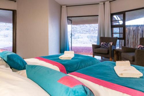 a hotel room with two beds with towels on them at Barkhan Dune Retreat in Solitaire