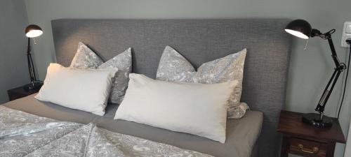 a bed with white pillows and a gray headboard at Altes Pastorat in Barmstedt