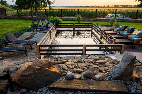 a pond in a yard with two benches and a rock at Galerie mlýn Žeraviny in Žeraviny