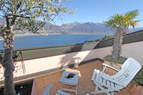 two white chairs sitting on a patio with a view of a lake at Orizzonte Blu by HolAp SA in Gambarogno