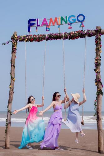 three girls on a swing on the beach at Flamingo Hai Tien in Nam Khê