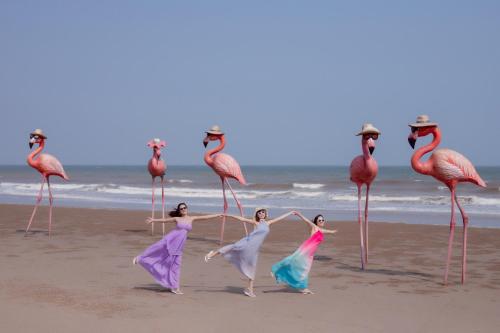 four women dancing on the beach with flamingos at Flamingo Hai Tien in Nam Khê