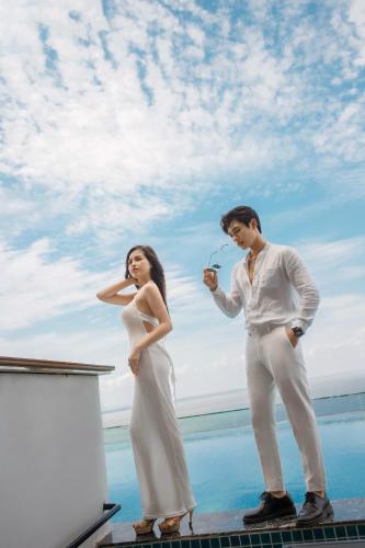 a man and a woman standing next to the ocean at Flamingo Hai Tien in Nam Khê